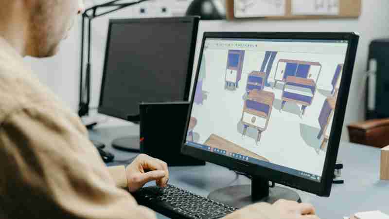 A product designer using a computer for 3D furniture modeling in an office setting., tags: modellazione - pexel