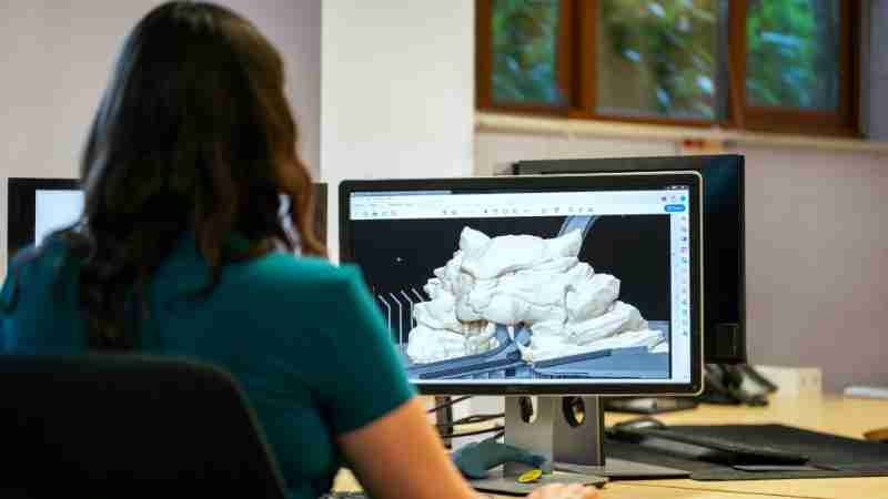 A woman using CAD software for 3D modeling in an office setting with a back view., tags: scultura - pexel